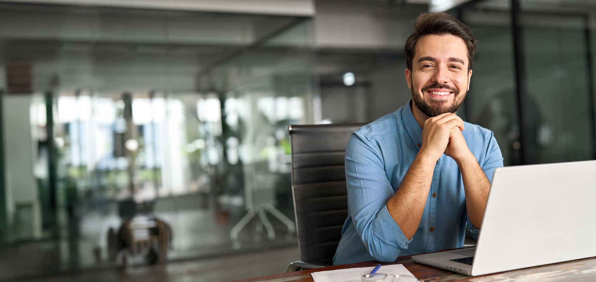 Smiling business owner at his desk with a laptop